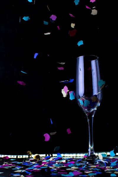 Glas champagne met confetti kleuren op achtergrond. — Stockfoto