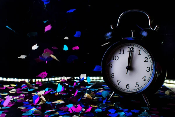 Reloj despertador con confeti con fondo negro . —  Fotos de Stock