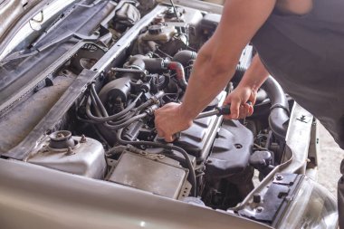 Araba motorunda ingiliz anahtarıyla çalışan tamirci..