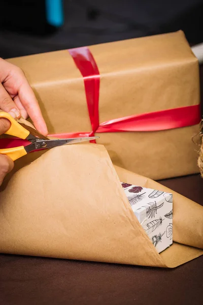 Person cutting the wrapping paper to wrap christmas presents.