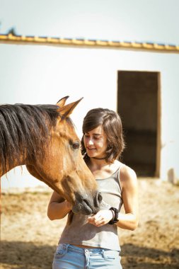 Rastalı bir kadın atını okşayıp oynuyor..