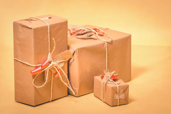 christmas gifts wrapped with cardboard paper on yellow background.
