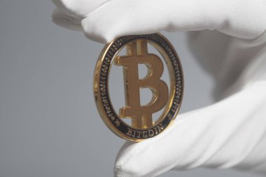 Beyaz eldiven elinde altın Bitcoin kripto para birimi tutar. Araştırma kavramı.