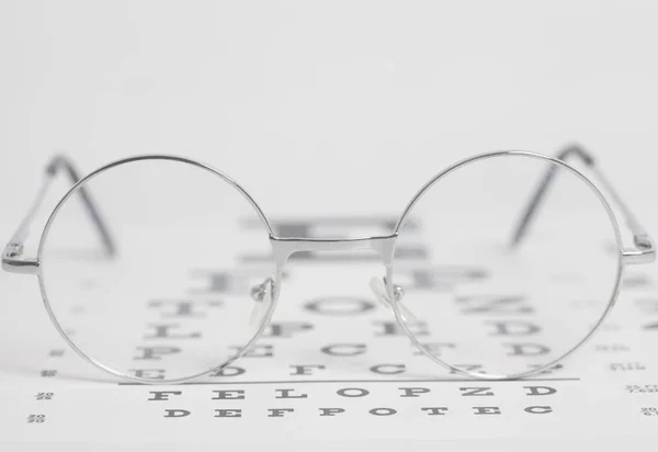 Eyeglasses on eyesight test chart background close-up.