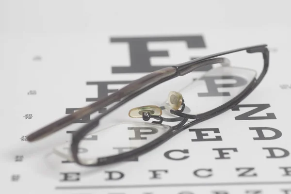 Óculos no fundo do gráfico de teste de visão . — Fotografia de Stock