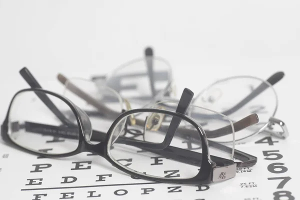 Eyeglasses on eyesight test chart background. — Stock Photo, Image
