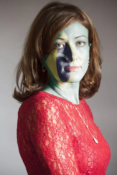 Portrait of woman with painted Flag of Brazil on a gray background