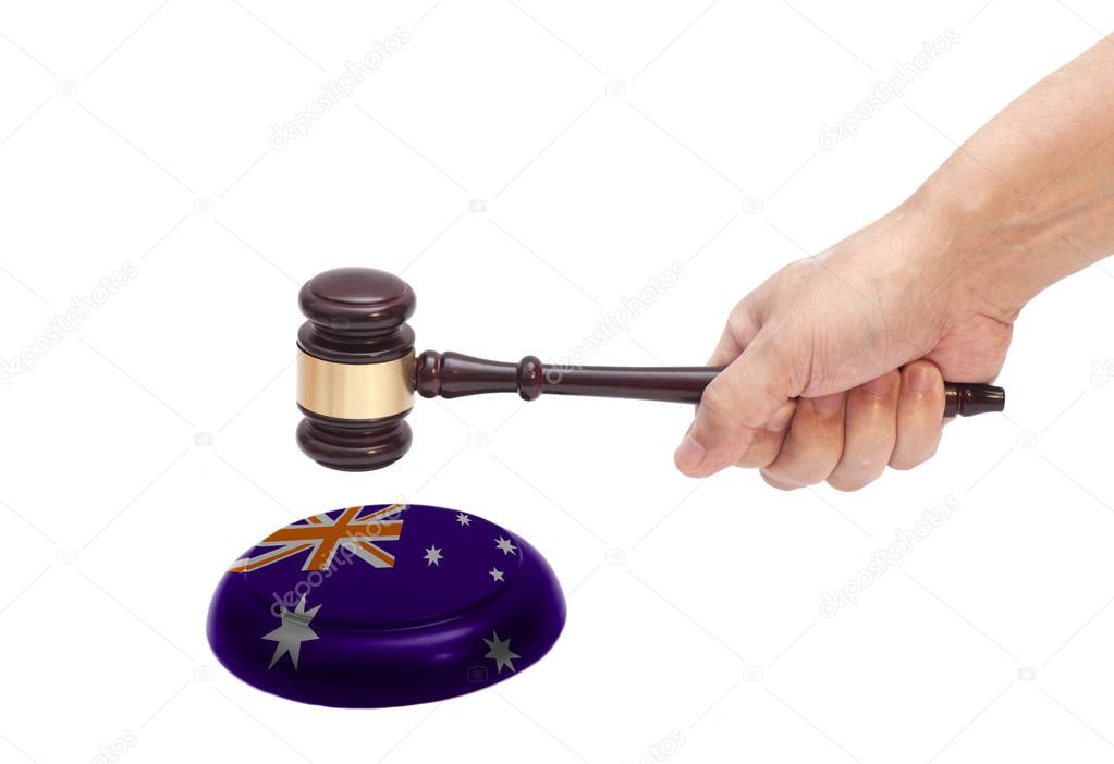 Hand knocking a Judge gavel at soundboard with Australia flag Isolated on white background