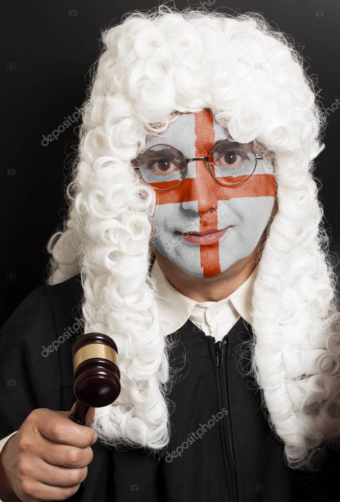 Portrait of male english lawyer with painted english flag holding judge gavel on black