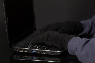 Hacker el eldiven içinde dizüstü bilgisayar üzerinde çalışıyor. Internet üzerinde siyah ceza kesmek kavramı