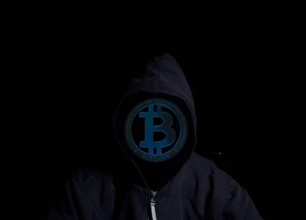 Anonymous Crypto Hacker in hood with bitcoin isolated on black background