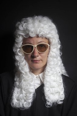 Siyah arka plan üzerine izole güneş gözlüklü bir peruk ve siyah manto giyen kadın yargıç