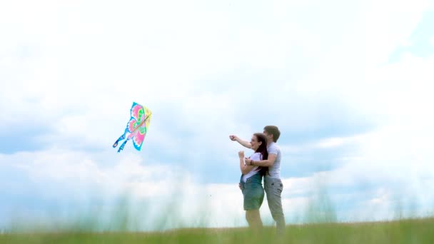 Familia joven, pareja corriendo una cometa contra un cielo azul y nubes — Vídeos de Stock