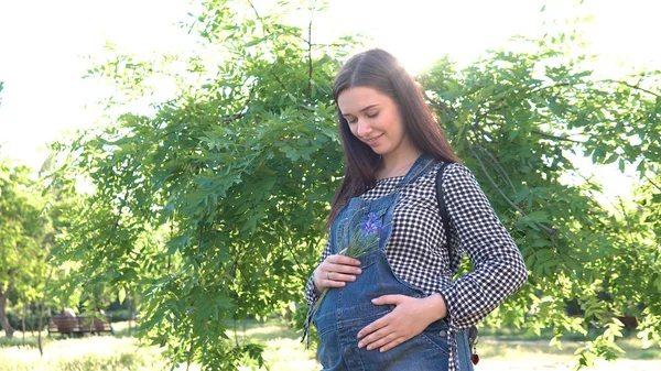 Tulum giymiş bir ağaç yakınındaki bir genç, güzel, hamile kız.