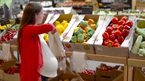 Junge Frau wählt Paprika in den Regalen. — Stockvideo