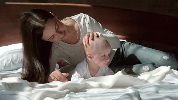 Close-up retrato de uma bela mãe sorrindo com o bebê na cama . — Vídeo de Stock