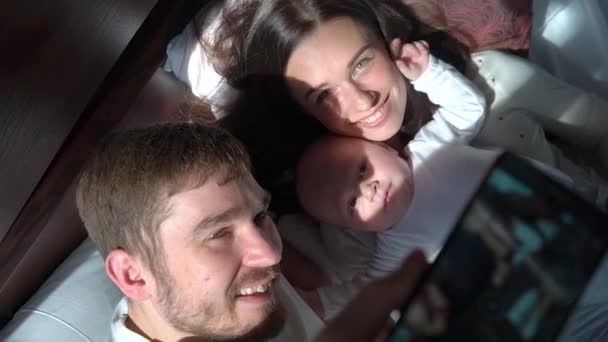 Família feliz alegre tomando selfie em uma cama, polegares para cima, sorrindo . — Vídeo de Stock