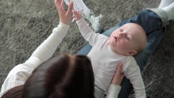 Retrato de cerca de una hermosa madre sonriendo con el bebé en el suelo — Vídeo de stock