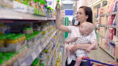 Süpermarkette alışveriş bebek oğlu ile güzel kadın, genç Anne pazarda çocukları için yiyecek seçer