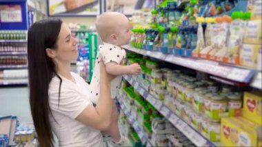 Süpermarkette alışveriş bebek oğlu ile güzel kadın, genç Anne pazarda çocukları için yiyecek seçer