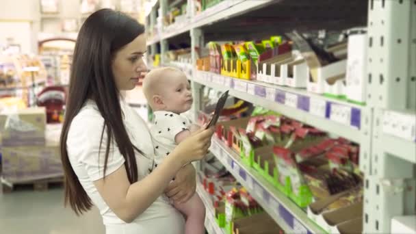 Mulher bonita com bebê filho compras no supermercado, jovem Mãe escolhe especiarias para sua família no mercado — Vídeo de Stock