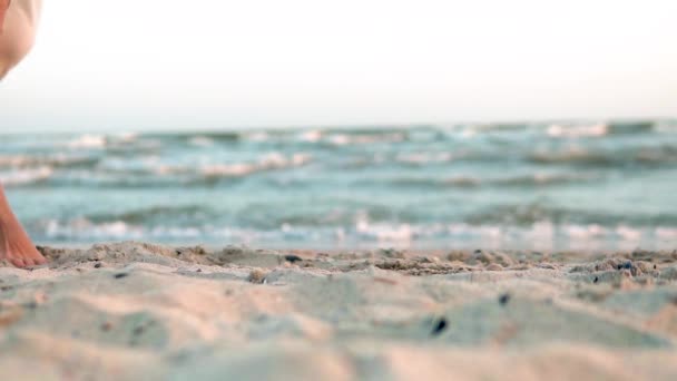 Beine eines kaukasischen Mädchens, das weißen langen Barfuß-Sand am Strand trägt, Sonne, Linse. Zeitlupe. Frau geht Kamera weg — Stockvideo
