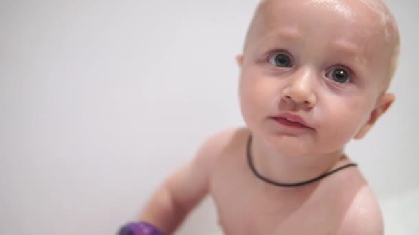 Een baby jongen badst in een bad met schuim en zeepbellen — Stockvideo