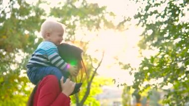 Genç bir anne ve küçük oğlu gülmek, girdap ve batan güneşin parlak ışınları fon karşı oynamak. Güzel doymuş renkler.