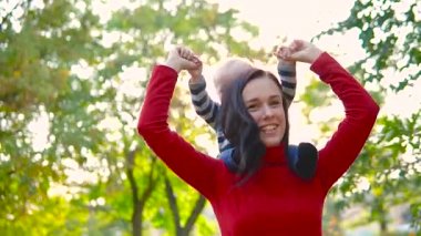 Genç bir anne ve küçük oğlu gülmek, girdap ve batan güneşin parlak ışınları fon karşı oynamak. Güzel doymuş renkler.