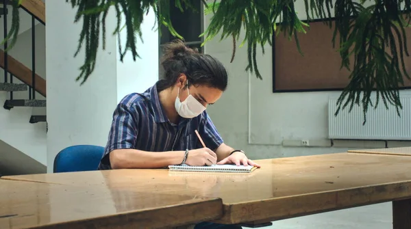 孤立した長い髪とマスク若い大学生は図書館で一人で勉強 ストックフォト