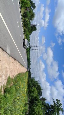 01 Ekim 2020: Reengus, Jaipur, Hindistan: Jaipur, Hindistan 'da elektrik kuleleri bulunan boş asfalt yol ve modern şehir silueti. Metal güvenlik bariyeri ya da tırabzanı olan yol. Bulutlu gökyüzünün altındaki asfaltta arabalar.