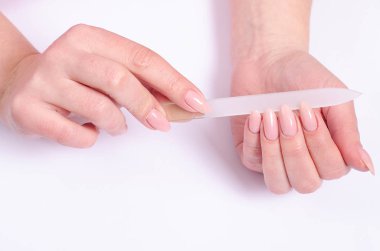 Gri bir arka plan üzerinde bir tırnak törpüsü ile manikür yapıyor kadın