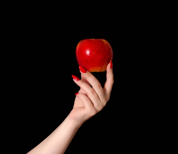 Red apple in the palm of the hand of a young woman on a black background closeup