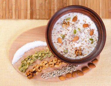 Ahşap arka plan üzerinde bir kil kase süt ile sağlıklı beslenme fındık.