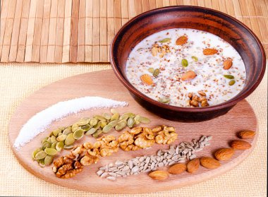 Ahşap arka plan üzerinde bir kil kase süt ile sağlıklı beslenme fındık.