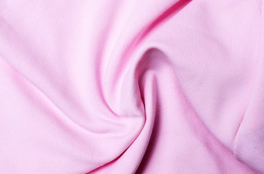 Yumuşak açık pembe sentetik kumaş spiral şekle bürünmüş modern moda tasarımı ve şık dekoratif kavramları için pürüzsüz tekstil arkaplanı oluşturuyor.