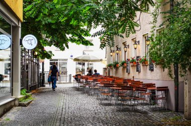 AUGSBURG, GERMANY 27 HAZİRAN 2025: Kentsel cadde güneşli bir yaz gününde çok az yayaya sahip çok sayıda konut binası ve boş bir açık kafeterya ile sıralanmış 