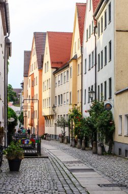 AUGSBURG, GERMANY 27 HAZİRAN 2025: Kentsel cadde güneşli bir yaz gününde çok az yayaya sahip çok sayıda konut binası ve boş bir açık kafeterya ile sıralanmış 