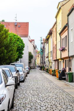 AUGSBURG, GERMANY 27 HAZİRAN 2025: Kentsel cadde güneşli bir yaz gününde çok az yayaya sahip çok sayıda konut binası ve boş bir açık kafeterya ile sıralanmış 
