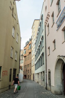 AUGSBURG, GERMANY 27 HAZİRAN 2025: Kentsel cadde güneşli bir yaz gününde çok az yayaya sahip çok sayıda konut binası ve boş bir açık kafeterya ile sıralanmış 