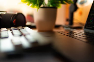 Bilgisayar, bitkiler ve sıcacık ışıklandırmanın yer aldığı modern masa kurulumu arka planı. Yaratıcı çalışma alanı, ev ofisi, masaüstü ilham kaynağı ve teknoloji temalı projeler için mükemmel..