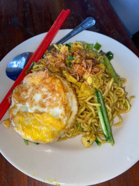 Kızarmış sebzeli erişte, beyaz tabakta yumurta.