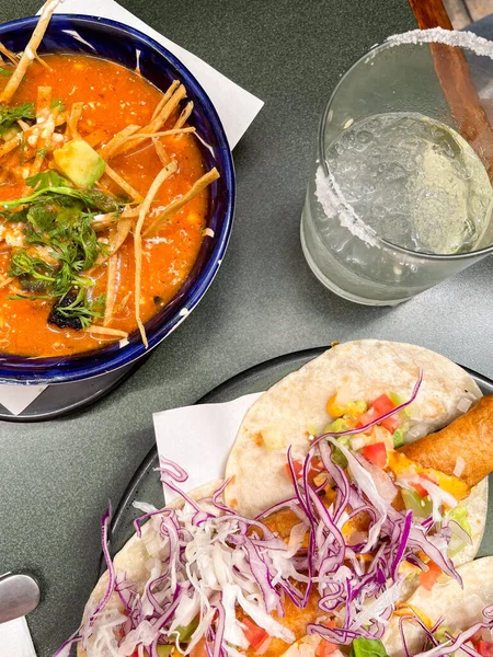 Meksika restoranında bir masa, margarita kokteyli, balıklı taco ve tortilla çorbası birlikte servis ediliyor..
