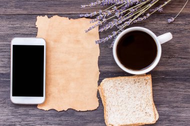 Eski kağıt, akıllı telefon, dilim ekmek ve kahve koyu ahşap masa arka plan üzerinde lavanta çiçeği ile. kopya alanı ile Üstten Görünüm
