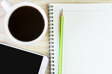 Akıllı telefon, kahve ve ahşap masa arka plan üzerine kalemle boş kitap. Üstten Görünüm