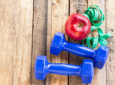 Mavi halter, ölçme bant ve ahşap masa üzerinde kırmızı elma. Fitness kavramı
