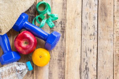 Mavi dambıl, havlu ve ahşap masa üzerinde su şişesi. Fitness kavramı