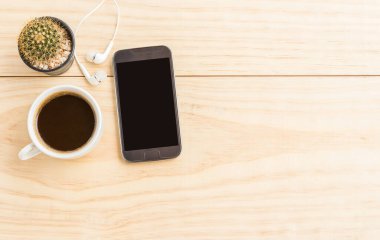 Kahve fincanı ve kopya alanı ile ahşap masa üstünde smartphone. Üstten Görünüm