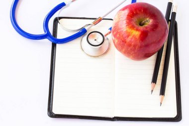 Kırmızı elma ve üstünde beyaz bir arka plan üzerinde defter stetoskop