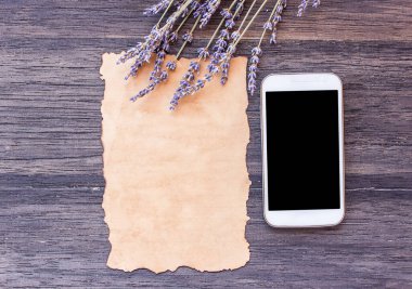 Tablo arka plan eski kağıt ve koyu ahşap lavanta çiçek ile akıllı telefon. kopya alanı ile Üstten Görünüm